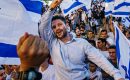 Bezalel Smotrich is hoisted up by Israelis as they dance and wave the national flag rally outside the Old City’s Damascus gate for the annual flag march in Jerusalem on June 15, 2021. (Photo: Marcus Yam/Los Angeles Times)